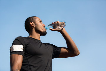 Man resting and drinking water after running