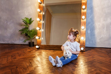 Easter celebration, pet care and animals concept. Cute happy little girl sitting on floor, holding...