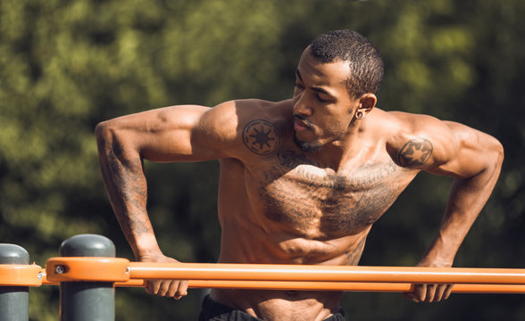 African-american athlete doing exercises on parallel bars