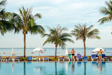 Obraz premium W godzinach porannych ludzie relaksują się między basenem a tropikalnym morzem.