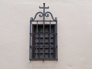 church window with iron grid and cross