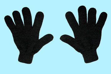 A pair of grey winter knitted gloves. Vertically. On a blue background. The view from the top. Isolated.
