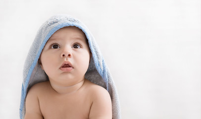 Surprised baby in bath hoodie towel on white background