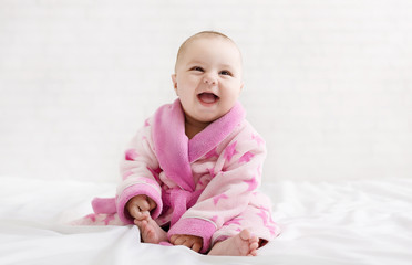 Little cute girl in pink bathrobe on white background