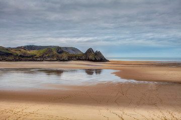 Reflections in a beach pool at Three Cliffs Bay, Gower, Swansea, UK