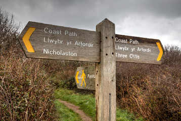 A bilingual Welsh and English signpost on the beach on the Gower peninsula in Swansea, South Wales, UK