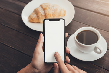 Woman hand using blank smart phone during breakfast