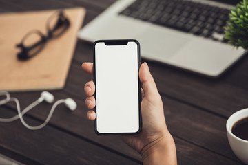 Woman with headphones using mobile phone with blank screen