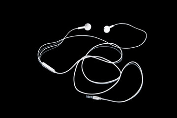 Wired headphones. Headphones music on a black background. Abstraction. White on black.