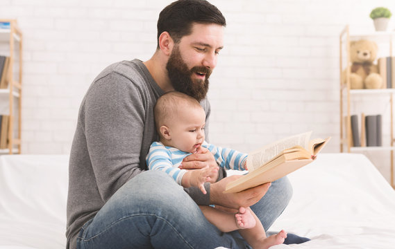 Father Reading Book To Little Baby Son