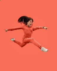 Freedom in moving. Mid-air shot of pretty happy young woman jumping and gesturing against coral...