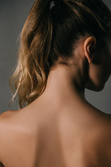 Obraz premium back view of blonde woman with ponytail on grey background
