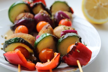 Grilled colorful vegetables skewers on white plate. Vegan meal.