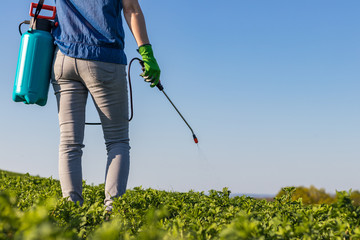 Female farmer spraying a field by crop sprayer at springtime