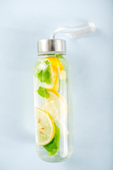 Homemade  lemonade in glass bottle, summer healthy drink concept, infused water, bright trendy background top view copy space
