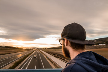Guy looking at a sunset .Portrait of a modern guy with cap and sunglasses . Concept of freedom and...
