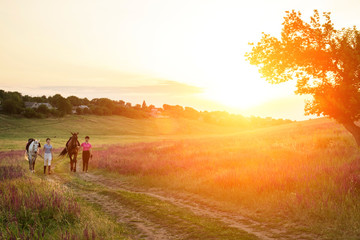 Two woman and two horses outdoor in summer happy sunset together nature