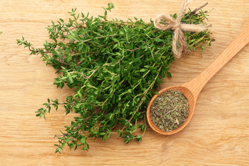green thyme bunch with dried thyme seeds on wooden background. top view