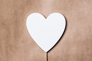 White wooden heart shape on brown rustic paper. Valentines day background.