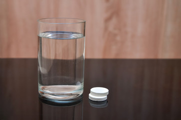 Anesthetic tablet, vitamins, in a glass of water with bubbles on a black table. Copy-space.