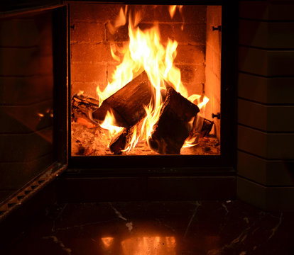 In an open fireplace burning fire.