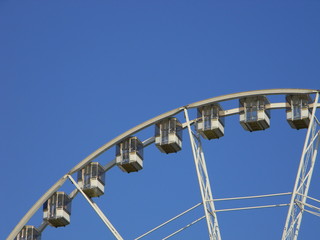Ferris wheel with empty cabins against sky background