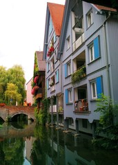 Naklejka premium Ulm, Germany - August 23 2018: View of one of Ulm's canals at Fischerviertel, with typical architecture along the banks and two women standing on a bridge in the background
