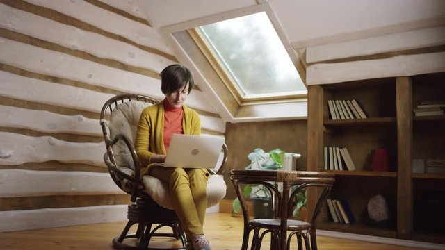 Adult woman surfing the Internet on laptop sitting in chair