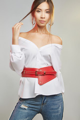 Three quarter portrait of a pretty lady with natural makeup, wearing jeans and blouse with cutaway...