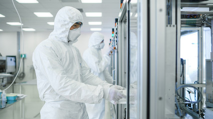 In the Manufacturing Facility Team of Scientist Wearing Sterile Protective Coverall Set's up /...