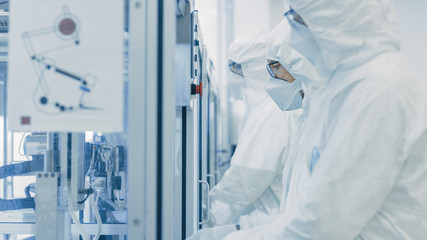 On a Factory Team of Scientists in Sterile Protective Clothing Work on a Modern Industrial 3D...