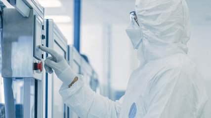 In Manufacturing Facility Scientist Wearing Sterile Protective Coverall and Programs Modern...