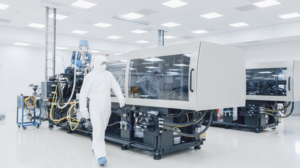 On a Factory Scientist in Sterile Protective Clothing Work on a Modern Industrial 3D Printing...