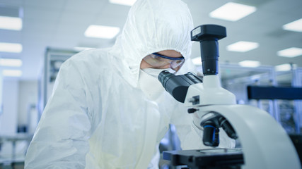 In Laboratory Scientist in Protective Clothes Doing Research Uses Microscope. Modern Manufactory...
