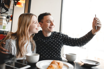 Happy couple are making selfie in cafe