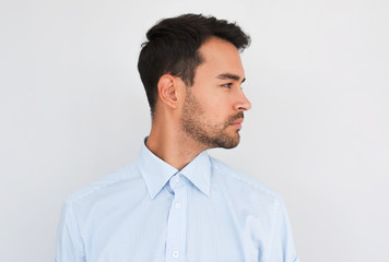 Profile view of handsome young handsome male wearing light blue shirt looking to the copy space for advertisement, posing on white studio background. People concept