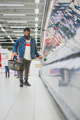 At the Supermarket: Full Length Vertical Shot of a Stylish African American Guy Dances Through Fresh Produce Section of the Store. Having Fun Shopping while Other Customers Smile.