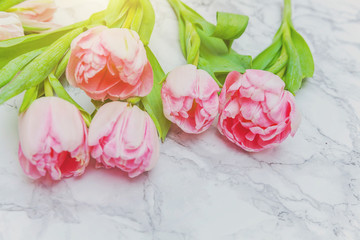 Spring greeting card. Bouquet of fresh light pastel pink tulips flowers on marble background. Happy holiday easter mother day anniversary valentine day birthday concept. Flat lay top view copy space