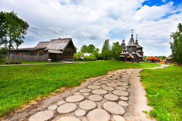 Road to the church.A traditional Russian village, a wooden church, a path stretches to the temple - obrazy, fototapety, plakaty