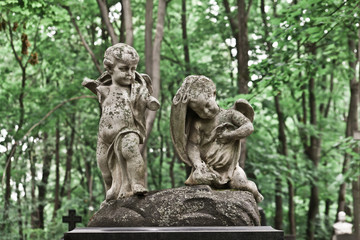 Fototapeta na wymiar The Sorrowful Angel. Mourning cherubs on a background of foliage