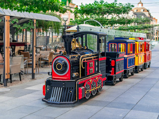 Children's summer attraction locomotive with cars on a city street