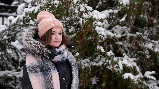 A young woman standing in the woods. Another woman come to her and shakes a branch and snow falls from trees