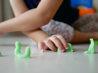 Little baby's hand playing playdough on the house floor - playing dough promotes baby's creativity, imagination, and fine motor skill development