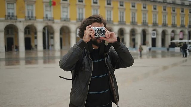 Excited bearded tourist with camera on square.