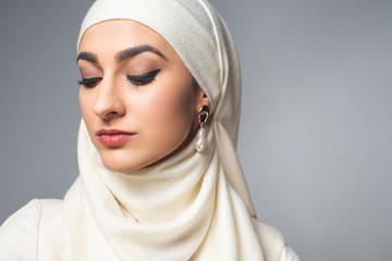 close-up portrait of beautiful young muslim woman looking down isolated on grey
