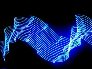 Light painting, long exposure photography, vibrant electric blue color ripples and waves against a black background