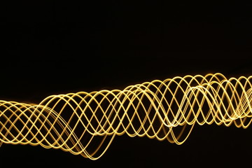 Light painting, long exposure photography, vibrant metallic gold color and motion against a black background