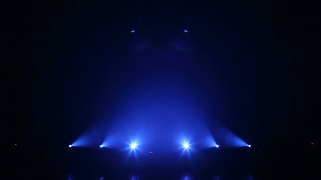Blue rays alternately flash on stage in the dark. Empty concert stage. Several bright blue spotlights on an empty stage in the dark. Bright beautiful rays of light on an empty stage before the concert