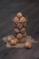 Whole walnuts in a glass jar on a rustic wooden background. Healthy food, snack.
