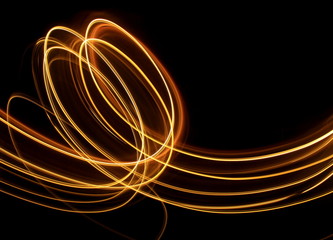 Light painting, long exposure photography, vibrant gold color against a black background